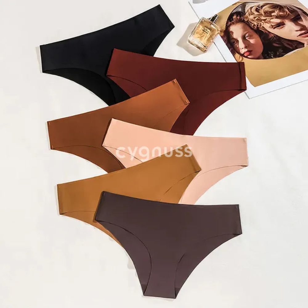 Imagem de calzones sin costuras da Cygnuss organizadas em tons terrosos, incluindo negro, marrón, caramelo y beige, dispostas sobre um fundo claro. Ao lado, uma revista y um frasco de perfume complementam a composição sofisticada.
