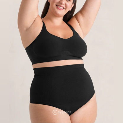 Mulher sorrindo con os braços erguidos, vestindo a calzón moldeador Pêra da Cygnuss, modelo tanga na color preta, con cintura alta canelada y top sin relleno combinando, evidenciando comodidad y leve compresión.
