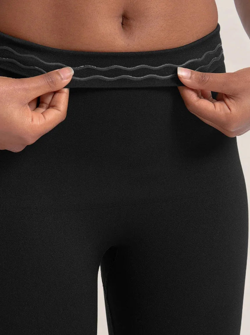 Close-up da Legging Jade Fit moldeador de Cós Alto na color preta, con foco no cós sendo levemente puxado para mostrar o detalhe interno em silicone antiderrapante que ajuda a manter a peça no lugar durante o uso.