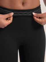 Close-up da Legging Jade Fit moldeador de Cós Alto na color preta, con foco no cós sendo levemente puxado para mostrar o detalhe interno em silicone antiderrapante que ajuda a manter a peça no lugar durante o uso.