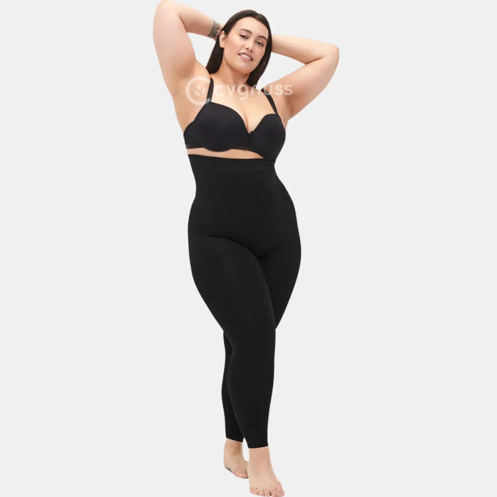 Mulher plus size usando a Legging Jade Fit moldeador de Cós Alto na color preta, em pose confiante con os braços erguidos, evidenciando o caimento cómodo, o cós alto y o ajuste que realza a silhueta.