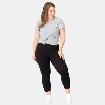 Mulher plus size usando a Legging Jade Fit moldeador de Cós Alto na color preta, combinada con camiseta gris amarrada y tênis blanco, em pose descontraída que evidencia o comodidad y a versatilidade da peça no dia a dia.