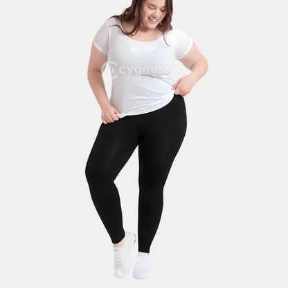 Mulher plus size sorridente usando a Legging Jade Fit moldeador de Cós Alto na color preta, combinada con camiseta branca y tênis, em pose descontraída que evidencia a versatilidade y comodidad da peça para o dia a dia.