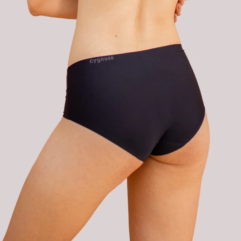 Vista traseira de uma mulher usando uma calzón preta sin costuras da Cygnuss. O modelo ajusta-se perfeitamente ao corpo, oferecendo comodidad y um acabamento discreto.