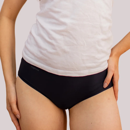 Mulher vestindo uma camiseta branca y uma calzón preta sin costuras da Cygnuss. A imagem destaca o ajuste cómodo da peça y seu design discreto, ideal para o dia a dia.