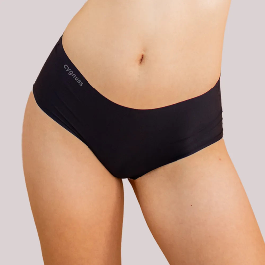 Imagem em close da região do quadril de uma mulher usando uma calzón preta da Cygnuss. O modelo sin costuras proporciona um ajuste cómodo y discreto.