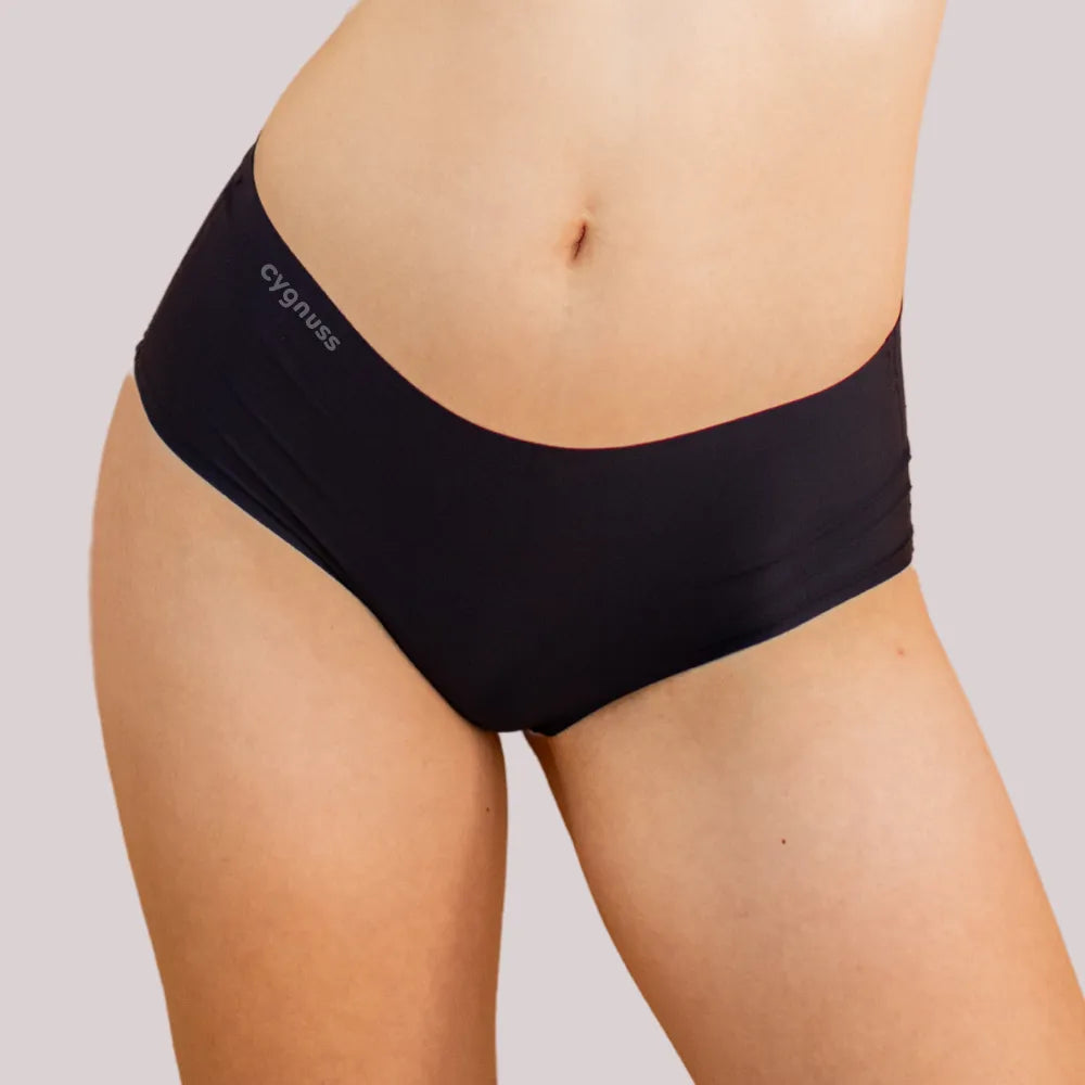 Imagem em close da região do quadril de uma mulher usando uma calzón preta da Cygnuss. O modelo sin costuras proporciona um ajuste cómodo y discreto.